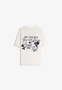 Witte katoenen t-shirt met marineblauwe bloem grafieken en tekst op de achterkant: "Kijk Niet Terug, Je Doet Het Echt Goed."