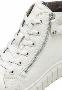 Zapatilla alta blanca de cuero con acabado texturizado, que cuenta con cierre de cremallera, parte delantera con cordones y suela de goma con patrón de banda de rodadura estriada.