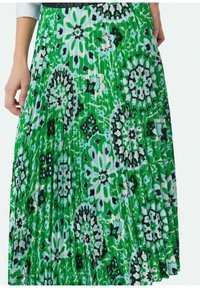 Lange geplooide rok met een levendige groene stof met bloemen- en geometrische patronen in zwart en lichtblauw.