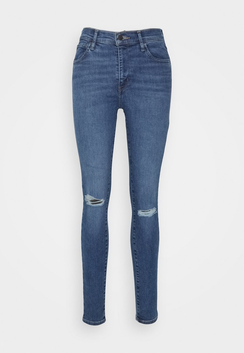 Schlanke Jeans aus dunkelblauem Denim mit hoher Taille, versehen mit ausgefransten Knieflicken und klassischem Fünf-Taschen-Design. Glatte Textur, minimale Nähte.