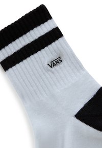 Calza bianca al ginocchio con texture a coste, caratterizzata da due strisce nere sulla parte superiore e un piccolo logo "VANS" nero sul lato.