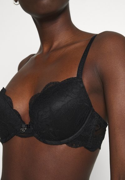 Svart blonde BH med underwire, bølgende kanter og en liten metallklips foran. Delikat blomsterdesign gjennom materialet.