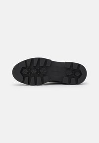 Suela de zapato de goma negra con surcos profundos y patrones hexagonales, talla 37, sobre un fondo blanco.