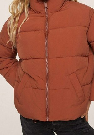 Steppend donzen jasje in roestrode kleur met rits aan de voorkant, zijzakken en hoge kraag, gedragen over een zwarte broek.