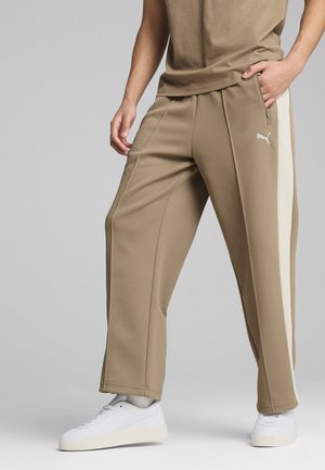 Khaki joggers met lichtbeige zijstrepen, gemaakt van zachte stof. Heeft een ritszak en een relaxte pasvorm. Gecombineerd met witte sneakers.