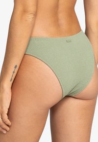 Zelené texturované spodní díly plavek s vysokým pasem a minimálním pokrytím. Obsahuje jemný logotyp na pásku.