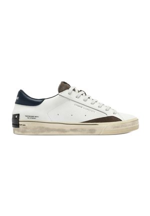 Sneaker bianca low-top con accenti marroni e neri, lacci e suola consumata, con testo "Distressed with no stress" sul lato.