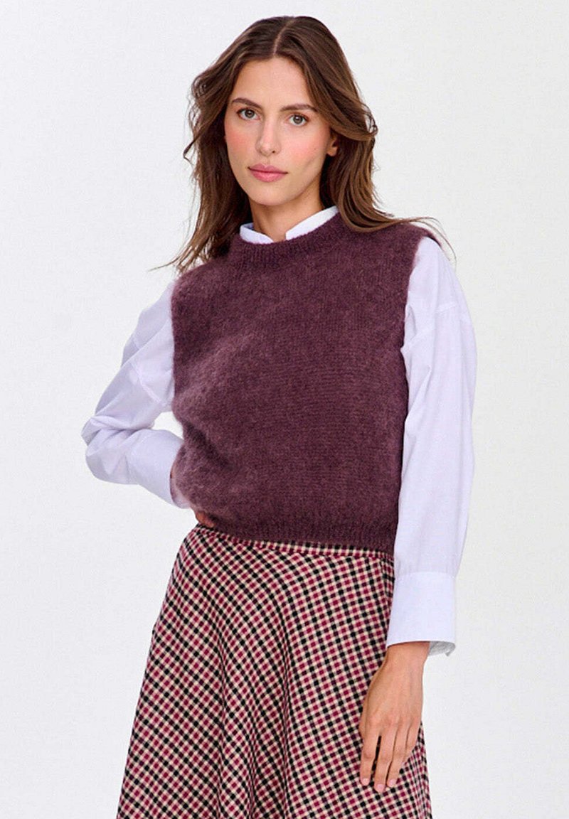 Hedvábný bezrukávový top v tmavě burgundské barvě, s texturovaným povrchem, spárovaný s bílou košilí s límečkem a kostkovanou sukní v růžových odstínech.