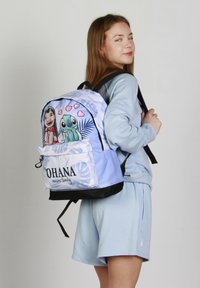 Mochila con una tela azul clara, personajes de dibujos animados en la parte frontal, texto que dice "OHANA significa familia" y un acento negro en la parte inferior.