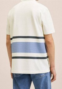 Polo blanc avec des rayures horizontales bleu foncé et bleu clair sur le dos. Le matériau semble doux avec une texture lisse.