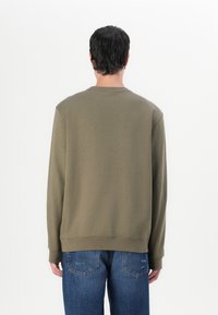 Olivenfarget sweatshirt med rund hals og ribbestrikkede mansjetter. Laget av mykt materiale, har en avslappet passform og minimalistisk design.