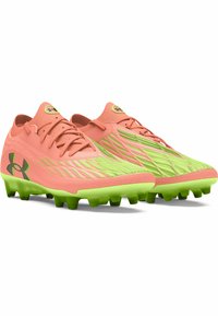 Rožinės ir žalios spalvos futbolo batai su tekstūruota viršutine dalimi, aerodinaminio dizaino ir kontrastingomis spalvomis. Dygliuotas padas, sukurtas sukibimui su žole.