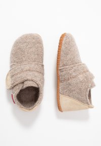 Jasnobrązowe filcowe kapcie o miękkiej teksturze, z rzepem, z zamszowymi akcentami i gumową podeszwą z teksturowanymi rowkami.