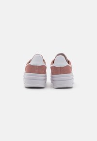 Ténis de camurça rosa com detalhes em pele branca, parte traseira arredondada, sola elevada e design texturizado. Linhas limpas e estética minimalista.