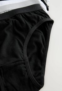 Schwarze Baumwollunterwäsche mit elastischem Bund, ausgestattet mit einem grauen Band, auf dem 'NEXT' eingeprägt ist. Glatte Textur, klassisches Briefdesign.