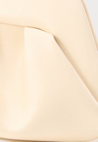 Τσάντα από απαλό δέρμα σε κρεμ χρώμα με μεγάλο εμπρόσθιο τσέπη και μινιμαλιστικό, ομαλό σχέδιο σε ουδέτερο φόντο.