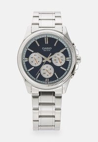 Montre-bracelet Casio argentée avec cadran bleu foncé, trois sous-cadrans pour 24 heures, jour et date, et bracelet à maillons en métal.