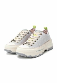 Zapatillas gris claro con un acabado texturizado, suela de goma crema y diseño de cordones. Presenta una lengüeta en verde y un forro interno a rayas.