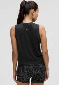 Top senza maniche nero con finitura texturizzata, caratterizzato da un collo rotondo e dettaglio del logo sulla schiena, abbinato a pantaloni corti neri con fantasia.