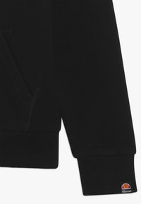 Sweatshirt noir avec poche kangourou, poignets et ourlet côtelés. Comprend un petit patch logo de marque coloré sur le poignet.