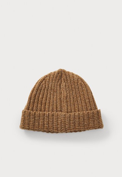Brūns adīts beanie cepure, kas izgatavota no strukturētas vilnas, iezīmējas ar ribota dizaina un salocītu apakšmalu, lai nodrošinātu papildu siltumu.