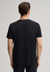 Zwarte katoenen t-shirt met korte mouwen, ronde hals en rechte zoom; zachte textuur met een klassieke pasvorm, zonder zichtbare logo's of patronen.