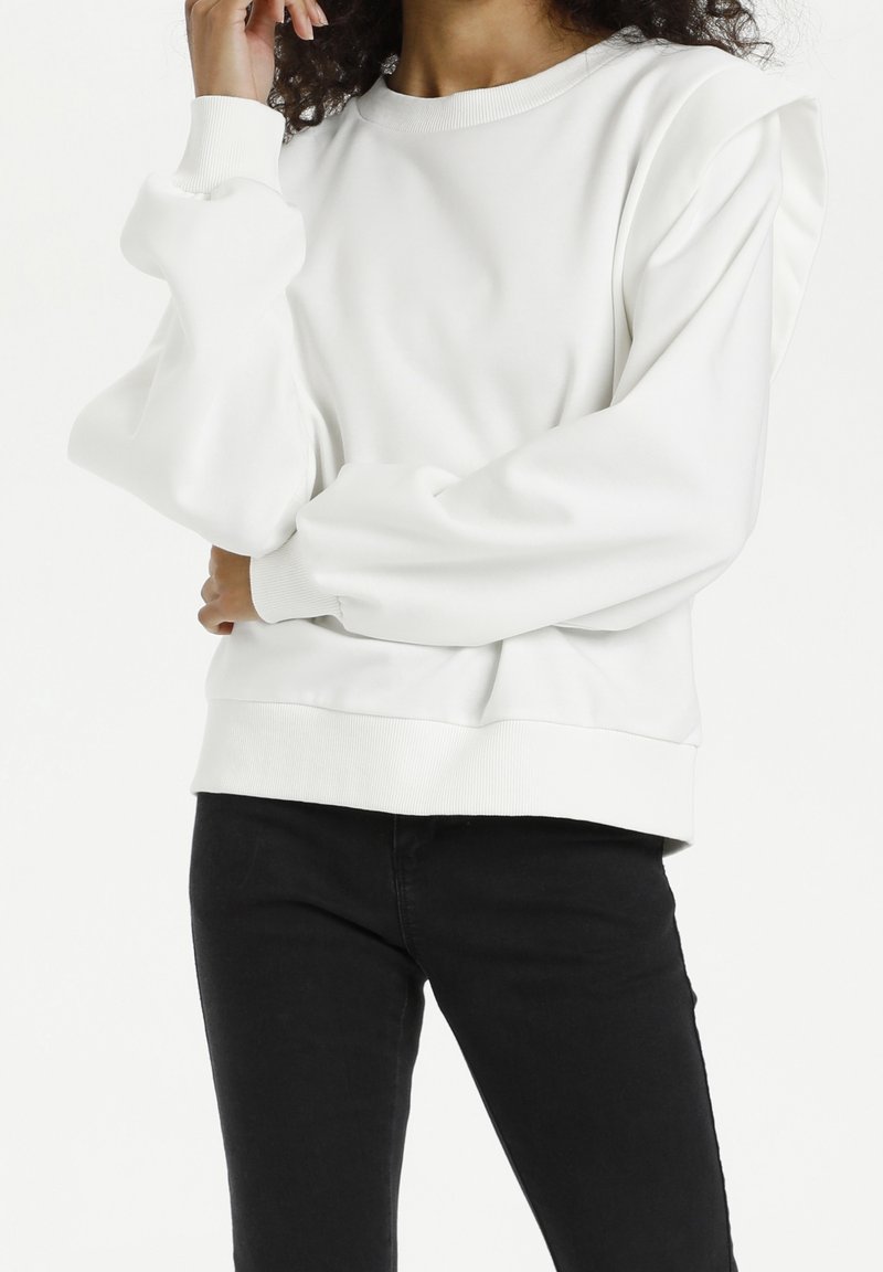 White sweatshirt with puffed sleeves, round neckline, and ribbed cuffs and hem. Material appears soft, with minimal seams and a relaxed fit.
