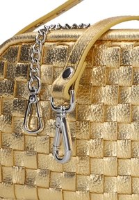 Goldfarbene Handtasche mit texturiertem metallischen Finish, ausgestattet mit einer Kettenschultertasche und silbernen Hardwareakzenten. Subtiles Karomuster über die gesamte Tasche.