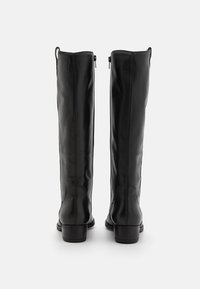 Schwarze Lederstiefel bis zum Knie mit glatter Textur, schrägen Nähten und einem niedrigen Blockabsatz. Es verfügt über einen Reißverschluss auf der Rückseite für ein einfaches Anziehen.
