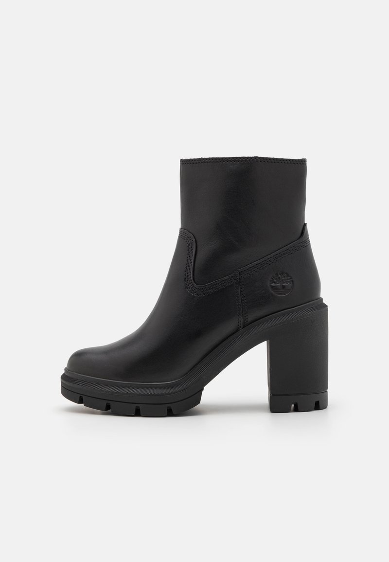 Bottine noire en cuir lisse. Présente un bout arrondi, un talon bloc, un côté élastique et une semelle en caoutchouc texturée avec un accent logo.