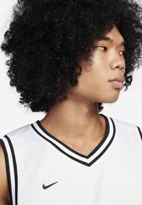 Hvid basketballtrøje med sort kant, med V-udskæring og Nike-logo. Modellen har krøllet sort hår og vises fra siden.