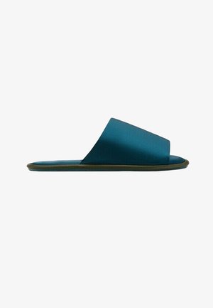 Enojni petrolejno modri natikač z širokim trakom in ravnim rjavim podplatom, prikazan v bočnem profilu na belem ozadju.