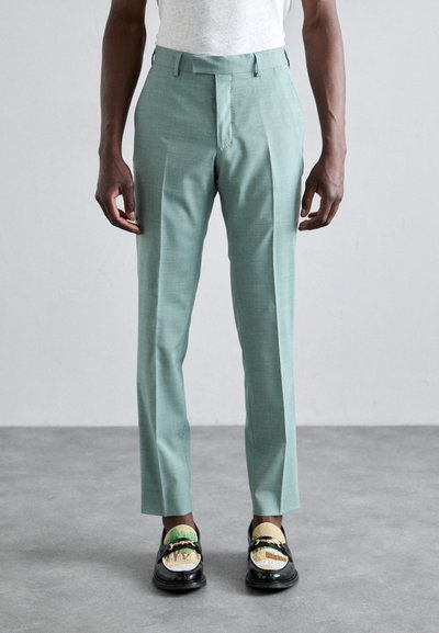 Jasnoniebieskie dopasowane spodnie o fakturowanym wykończeniu, slim fit, z plisami z przodu, w zestawieniu z czarnymi loafersami z wielokolorowymi akcentami.