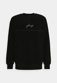 Felpa nera in pile con superficie testurizzata, polsini e orlo a coste, e un logo bianco sul petto. Design a girocollo.