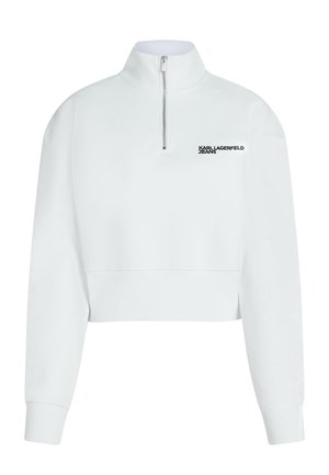 Bijela kratka majica dugih rukava s visokim ovratnikom, zatvaračem na pola i crnim logotipom "KARL LAGERFELD JEANS" na lijevoj strani prsa. Glatka tekstura.