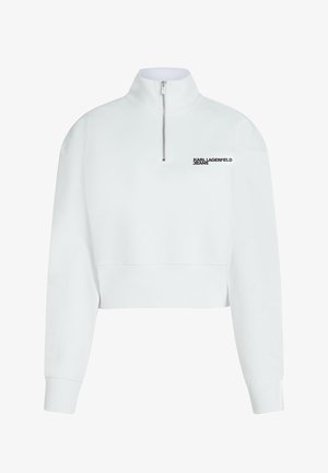Biely krátky sveter s vysokým golierom, polovičným zipsom a čiernym logom "KARL LAGERFELD JEANS" na ľavej strane hrude. Hladký textúra.