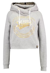 Lichtgrijze cropped hoodie met gouden "Superdry" logo, witte koordjes, geribbelde manchetten en zwarte merkvoering binnenin de capuchon.