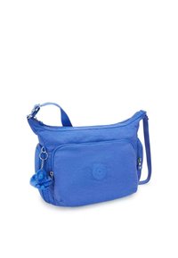 Borsa a spalla in nylon blu con design arrotondato, dotata di tasca frontale, tracolla regolabile e un charm a forma di scimmietta blu in peluche attaccato.