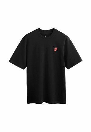 Čierne tričko s krátkym rukávom s malým červeným logom Rolling Stones s jazykom a perami na ľavej hornej strane hrudníka.