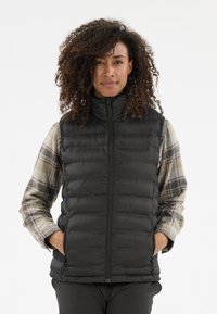 Schwarze, puffy Weste mit hohem Kragen und Reißverschluss, verziert mit horizontalen Nähten, kombiniert mit einem karierten Langarmhemd. Glatte Textur.