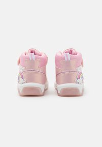 Roze hoge sneakers hebben een glanzende roze en witte afwerking, ademend mesh-materiaal, een regenboogontwerp op de hiel en een klittenbandsluiting.