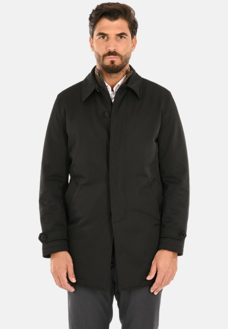 Cappotto nero fino al ginocchio con chiusura a bottoni, colletto appuntito e tasche laterali. Realizzato in tessuto liscio con una texture leggermente lucida.