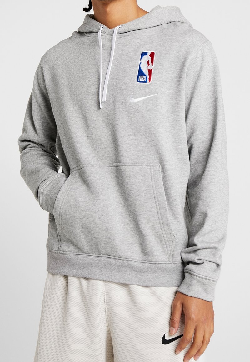 Sweat à capuche Nike gris en tissu doux, doté d'une poche frontale, d'une capuche ajustable et du logo NBA sur la poitrine en bleu, rouge et blanc.