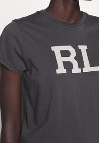 Tmavě šedé bavlněné tričko s kulatým výstřihem a krátkými rukávy, na přední straně s velkým bílým nápisem "RL". Hladká textura.