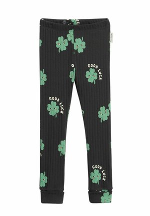 Zwarte geribde kinderbroek met groene prints van lachende klavertjes vier en de tekst "Good Luck" verspreid over de stof.