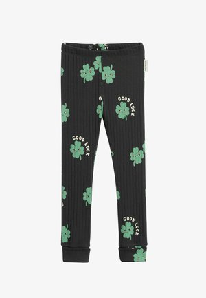 Zwarte geribde kinderbroek met groene prints van lachende klavertjes vier en de tekst "Good Luck" verspreid over de stof.