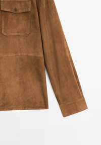 Braunes Wildlederhemd mit einer einzigen Brusttasche, langen Ärmeln und einer glatten Textur. Verfügt über einen Knopfverschluss und saubere Nähte.