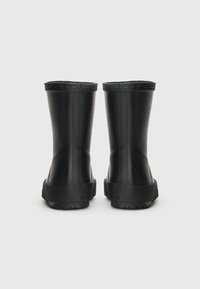 Bottes de pluie en caoutchouc noir avec une surface lisse, un profil bas et des semelles texturées. Les parties supérieures sont légèrement évasées, avec un détail de couture durable.