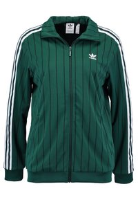 Grön zip-up jacka med vertikala svarta ränder, vita sidostripes och liten vit logotyp på bröstet. Har ståkrage och två fickor.