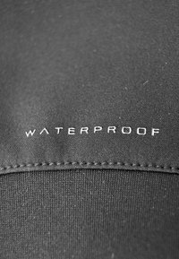 Tissu noir avec une texture lisse, présentant le mot "WATERPROOF" en lettres blanches brodées en bas.